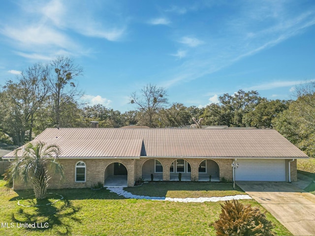 ranch-style house featuring a garage, concrete driveway, metal roof, a front lawn, and brick siding