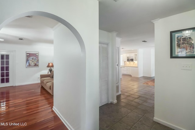 corridor with visible vents, dark tile patterned floors, and baseboards