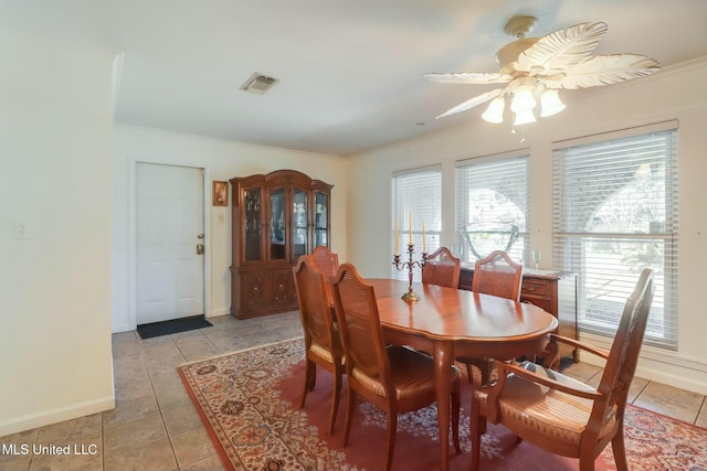 dining room with light tile patterned floors, baseboards, visible vents, a ceiling fan, and crown molding