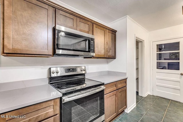 kitchen with dark tile patterned floors and appliances with stainless steel finishes