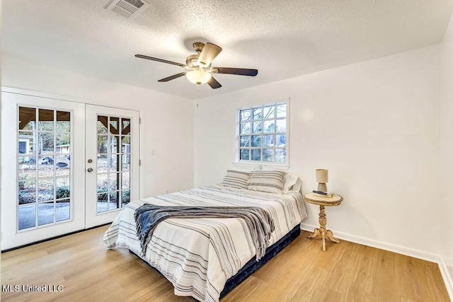 bedroom with hardwood / wood-style flooring, access to exterior, ceiling fan, a textured ceiling, and french doors