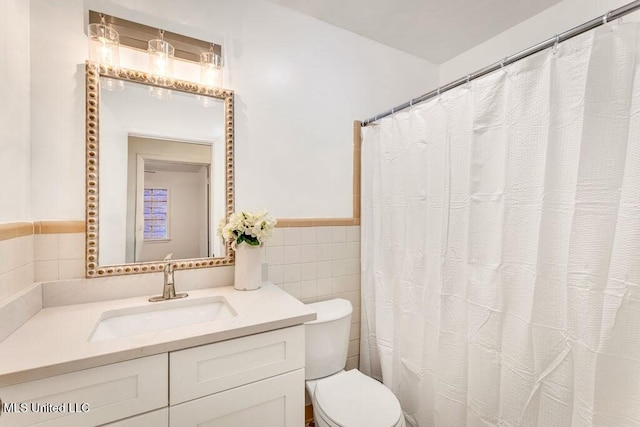 bathroom with tile walls, vanity, and toilet