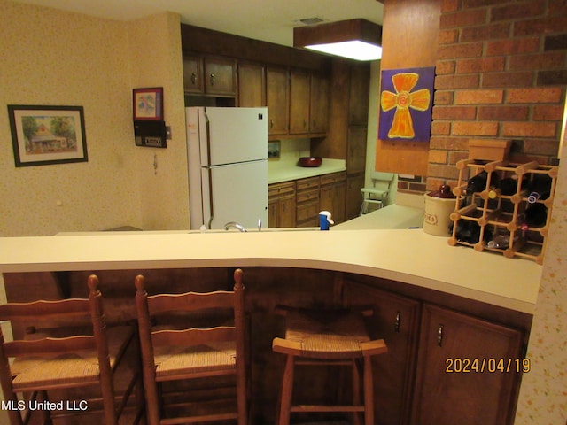 kitchen with white fridge, kitchen peninsula, and a breakfast bar