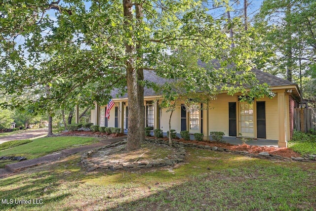 view of front facade with roof with shingles, a front yard, covered porch, and fence