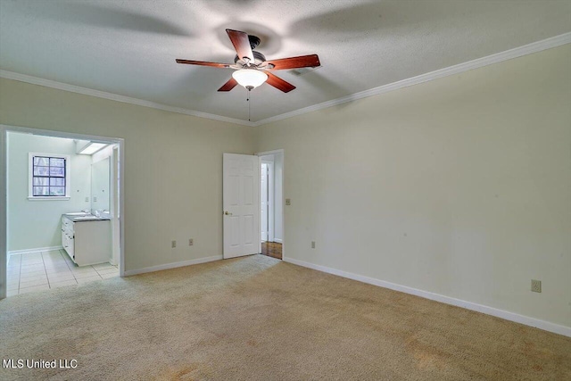empty room with ceiling fan, light carpet, ornamental molding, and baseboards