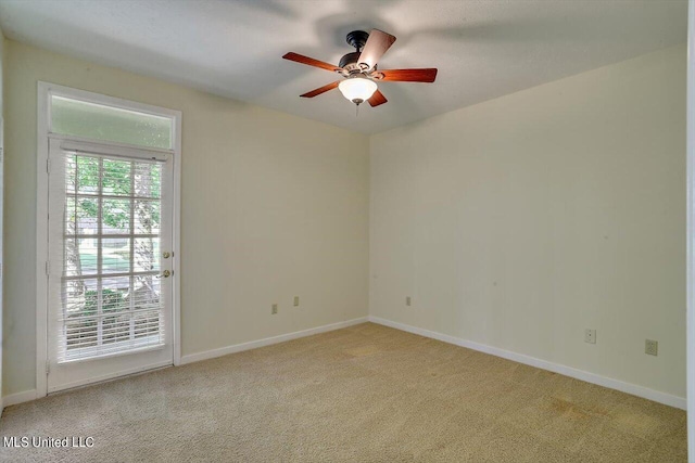 spare room with light colored carpet, baseboards, and a ceiling fan