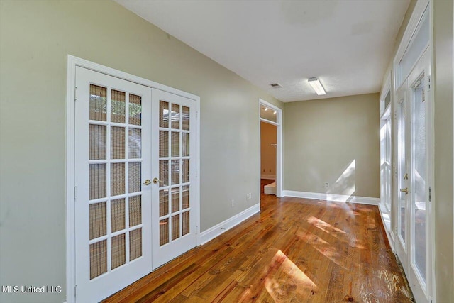 interior space with wood finished floors, visible vents, baseboards, and french doors