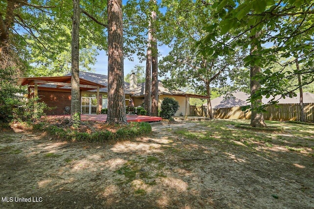back of house with a chimney, fence, and a deck