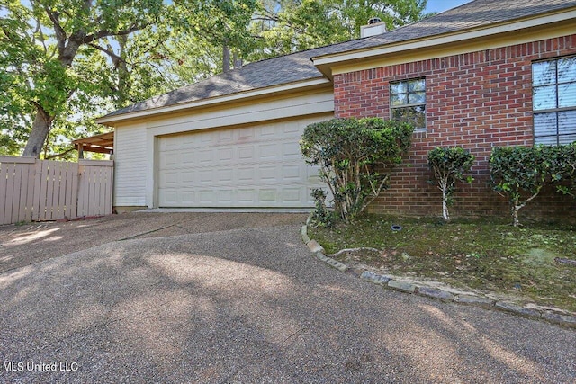 exterior space with a chimney, aphalt driveway, an attached garage, fence, and brick siding