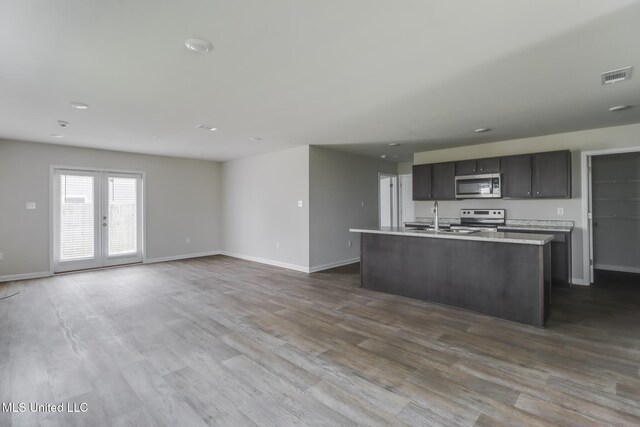2016 Carondelet St, Ocean Springs, MS 39564 - kitchen with stainless steel appliances, light countertops, a center island with sink, dark wood-type flooring, and french doors