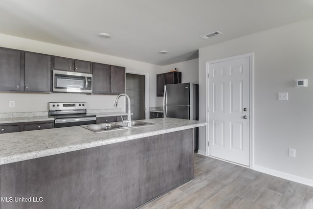 2016 Carondelet St, Ocean Springs, MS 39564 - kitchen with stainless steel appliances, dark brown cabinetry, and light wood-type flooring