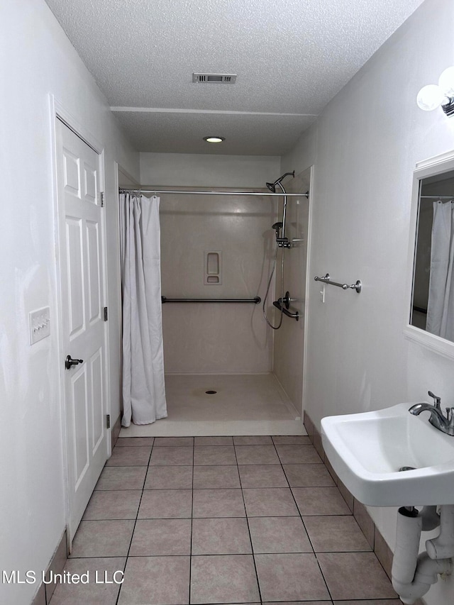 bathroom with a shower with shower curtain, a textured ceiling, and tile patterned flooring