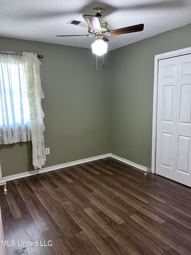 empty room featuring dark hardwood / wood-style floors, a textured ceiling, and ceiling fan