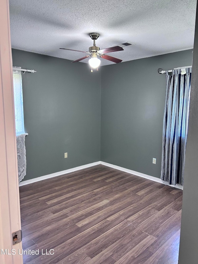 unfurnished room with a textured ceiling, dark wood-type flooring, and ceiling fan