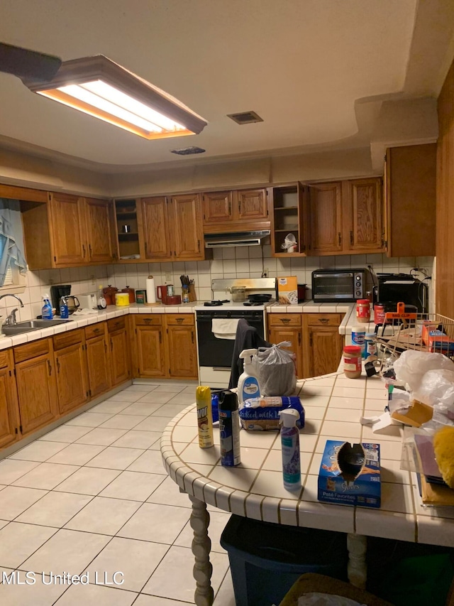 kitchen with tile countertops, white range oven, sink, light tile patterned flooring, and tasteful backsplash