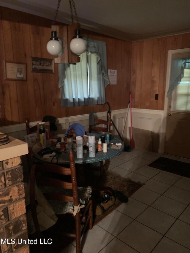 dining area featuring crown molding, wooden walls, and tile patterned flooring