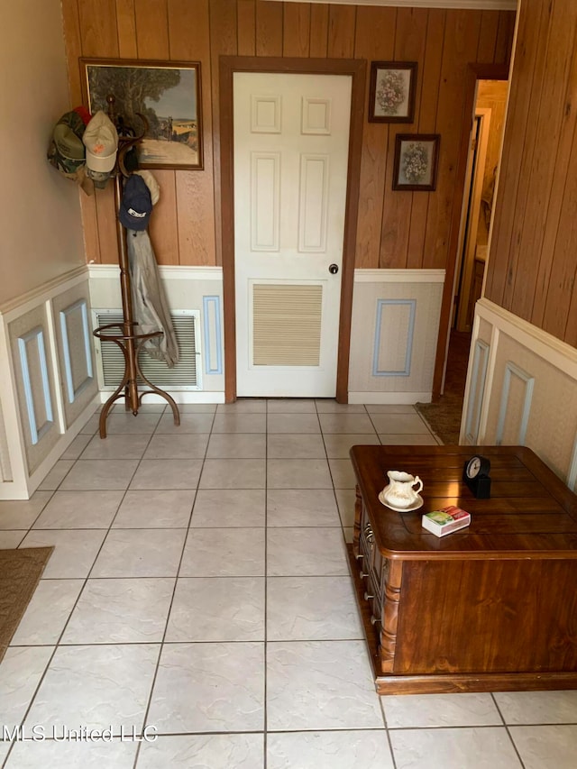 hall featuring wood walls and light tile patterned floors