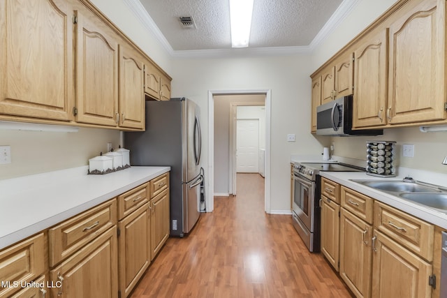 8921 Hanalei Cir, Diamondhead, MS 39525 - kitchen featuring appliances with stainless steel finishes, light countertops, light wood finished floors, a textured ceiling, and ornamental molding
