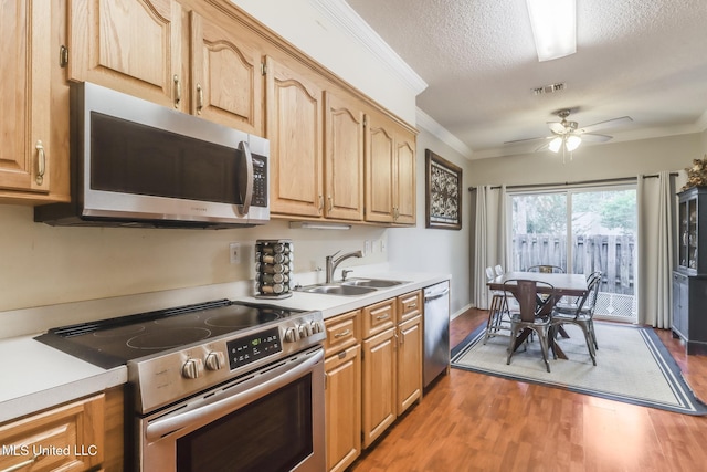 8921 Hanalei Cir, Diamondhead, MS 39525 - kitchen featuring stainless steel appliances, light countertops, a ceiling fan, light wood finished floors, and ornamental molding