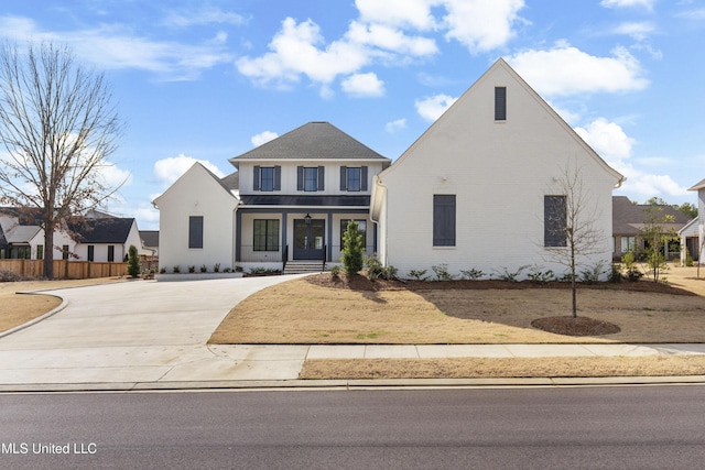 traditional home with covered porch, concrete driveway, brick siding, and fence