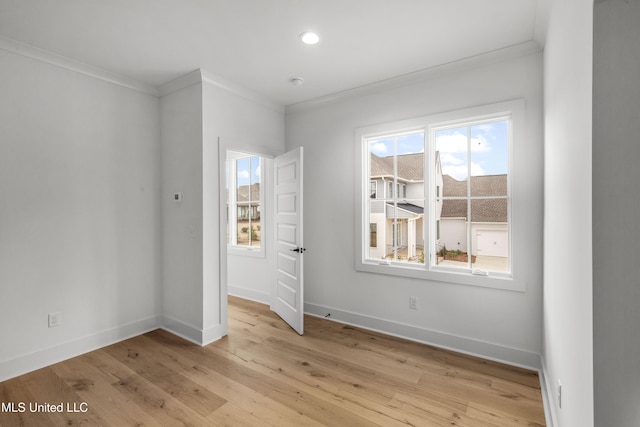 empty room featuring light wood finished floors, baseboards, and crown molding