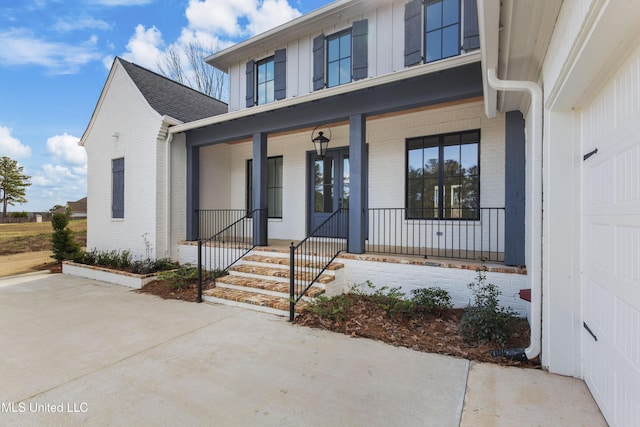 view of exterior entry with covered porch and brick siding