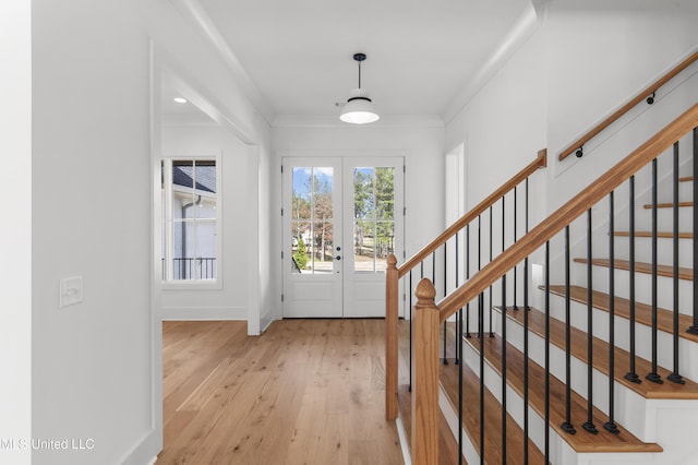 foyer featuring baseboards, stairway, light wood-type flooring, and crown molding