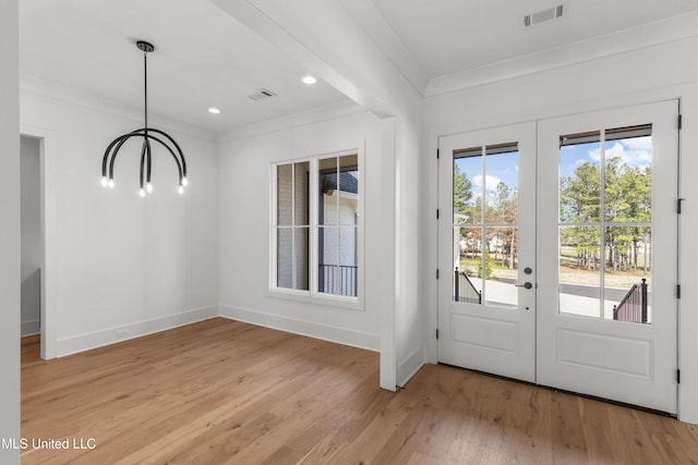 doorway with light wood finished floors, visible vents, ornamental molding, and french doors