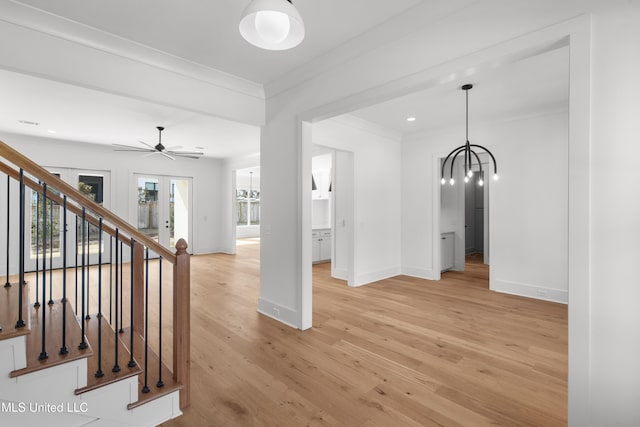 interior space featuring baseboards, crown molding, light wood finished floors, and stairs