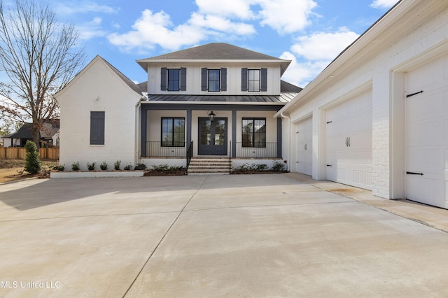 view of front of property with concrete driveway, metal roof, covered porch, a standing seam roof, and brick siding