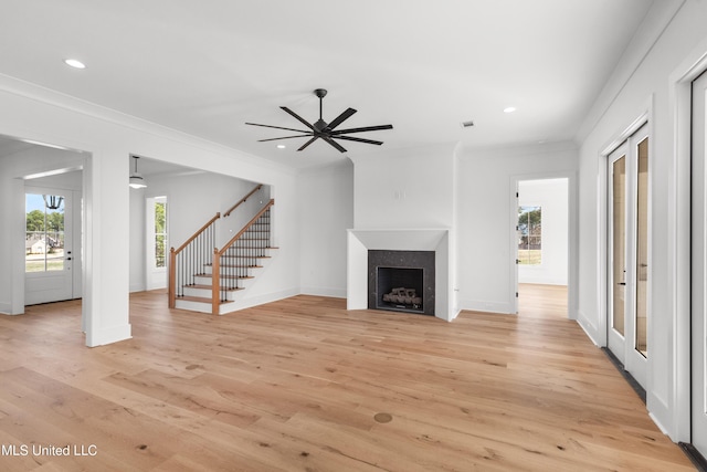 unfurnished living room with a fireplace, recessed lighting, stairway, ornamental molding, and light wood-style floors