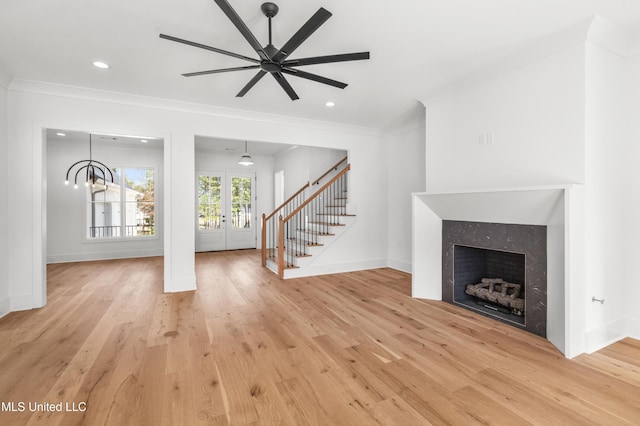 unfurnished living room with light wood finished floors, ornamental molding, stairway, and a tiled fireplace