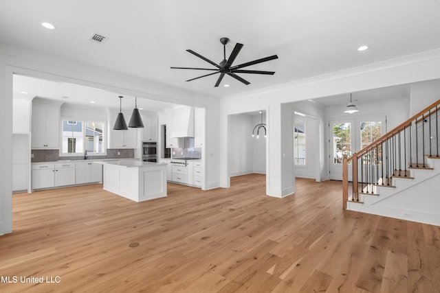 kitchen featuring a kitchen island, open floor plan, hanging light fixtures, light countertops, and white cabinetry