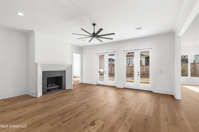 unfurnished living room featuring light wood-style floors, french doors, visible vents, and crown molding