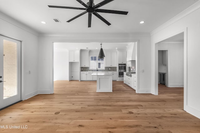 kitchen with visible vents, white cabinets, light countertops, decorative light fixtures, and crown molding