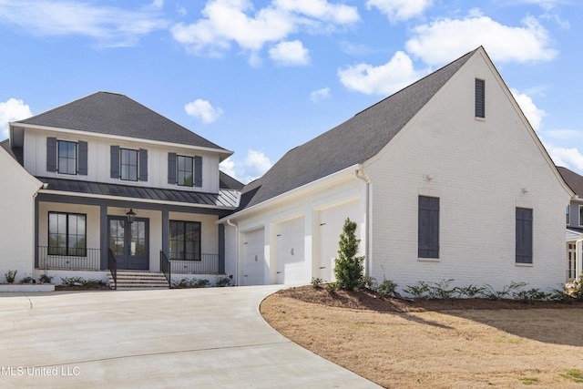 view of front of property featuring brick siding, covered porch, concrete driveway, a standing seam roof, and metal roof