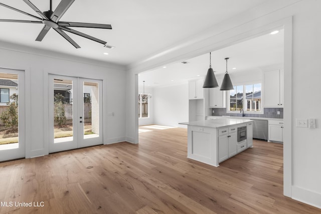 kitchen featuring a center island, white cabinets, light countertops, built in microwave, and pendant lighting