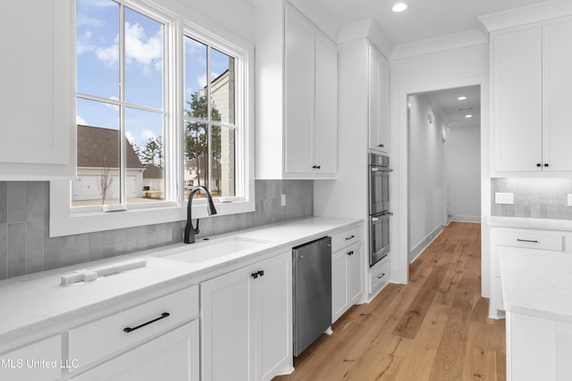 kitchen with white cabinets, dishwasher, a sink, and light stone countertops