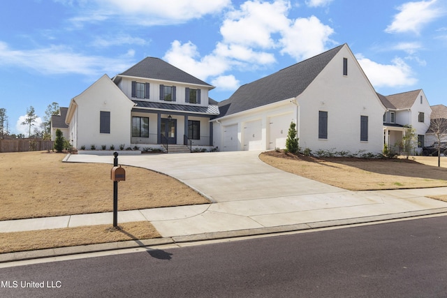 view of front of property with concrete driveway, metal roof, an attached garage, a standing seam roof, and a porch