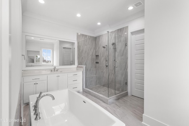 full bathroom with visible vents, crown molding, vanity, a freestanding tub, and a shower stall