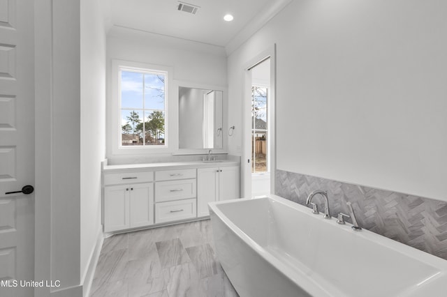 full bathroom featuring a wealth of natural light, a soaking tub, visible vents, and vanity