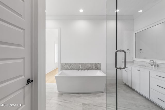 bathroom featuring a freestanding bath, vanity, and recessed lighting