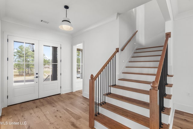 foyer with light wood finished floors, baseboards, visible vents, stairs, and french doors