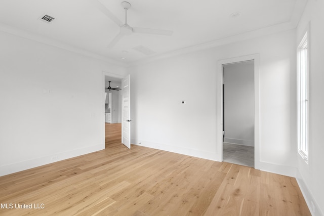 spare room featuring ornamental molding, light wood-style flooring, visible vents, and a ceiling fan