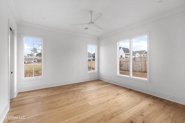 spare room featuring crown molding, light wood-style flooring, and baseboards