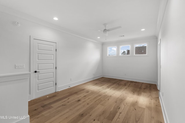 spare room featuring ceiling fan, ornamental molding, light wood-style flooring, and baseboards