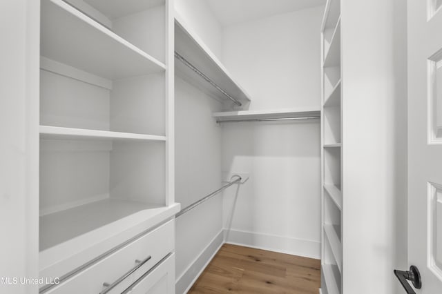 walk in closet with wood finished floors