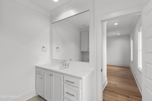 bathroom with recessed lighting, vanity, baseboards, and wood finished floors