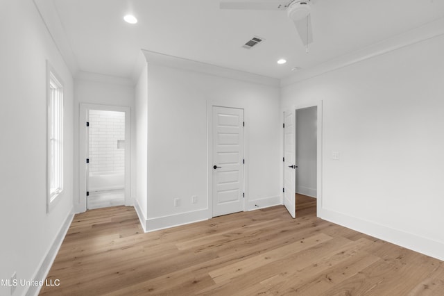 empty room featuring light wood finished floors, baseboards, visible vents, and ornamental molding