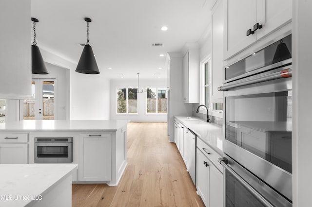 kitchen with light wood-type flooring, white cabinetry, light countertops, and decorative light fixtures